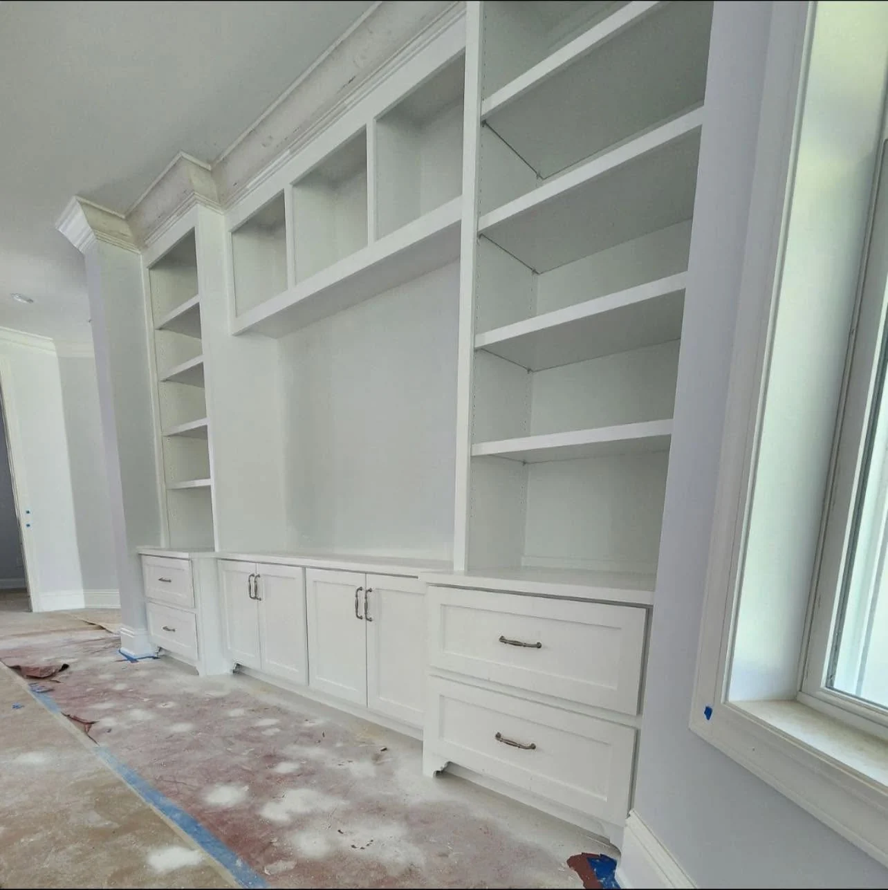 Wall-to-wall white built-in cabinetry and display shelving under construction