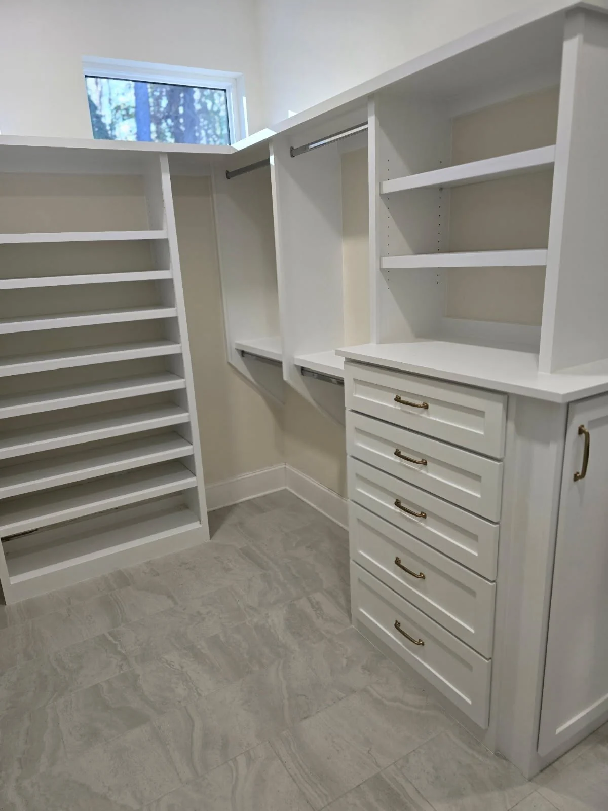Custom white walk-in closet with drawers, brass pulls, shelves and hanging rails