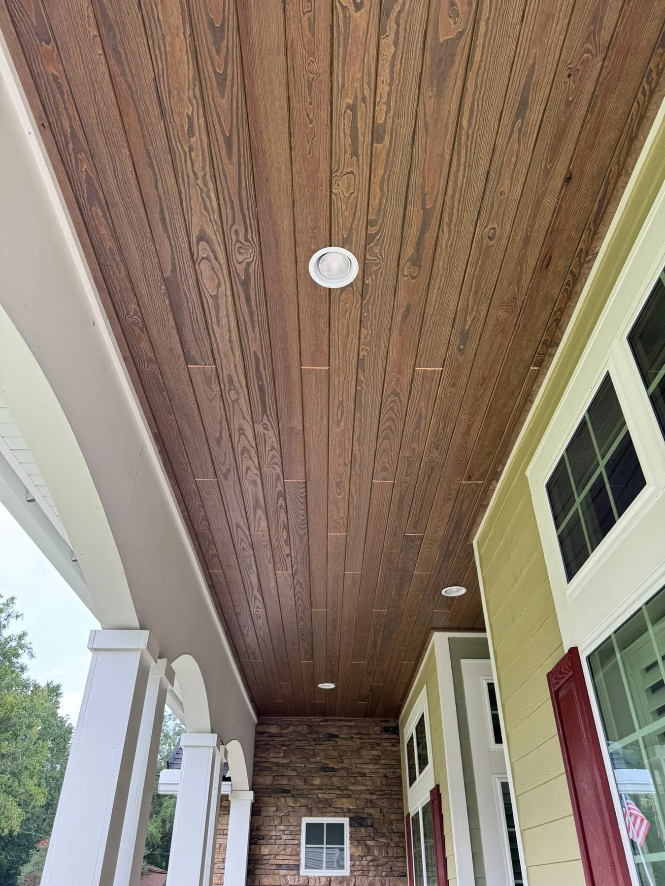 Dark-stained tongue-and-groove porch ceiling with recessed lights