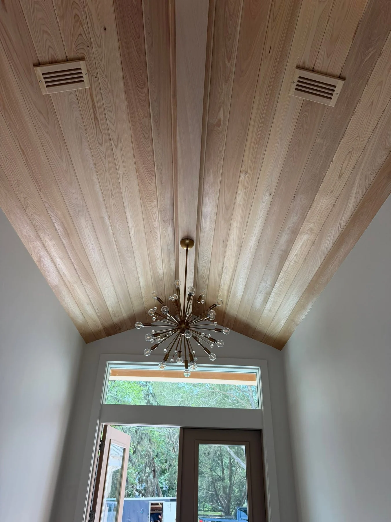 Natural-wood vaulted entry ceiling with a sculptural chandelier