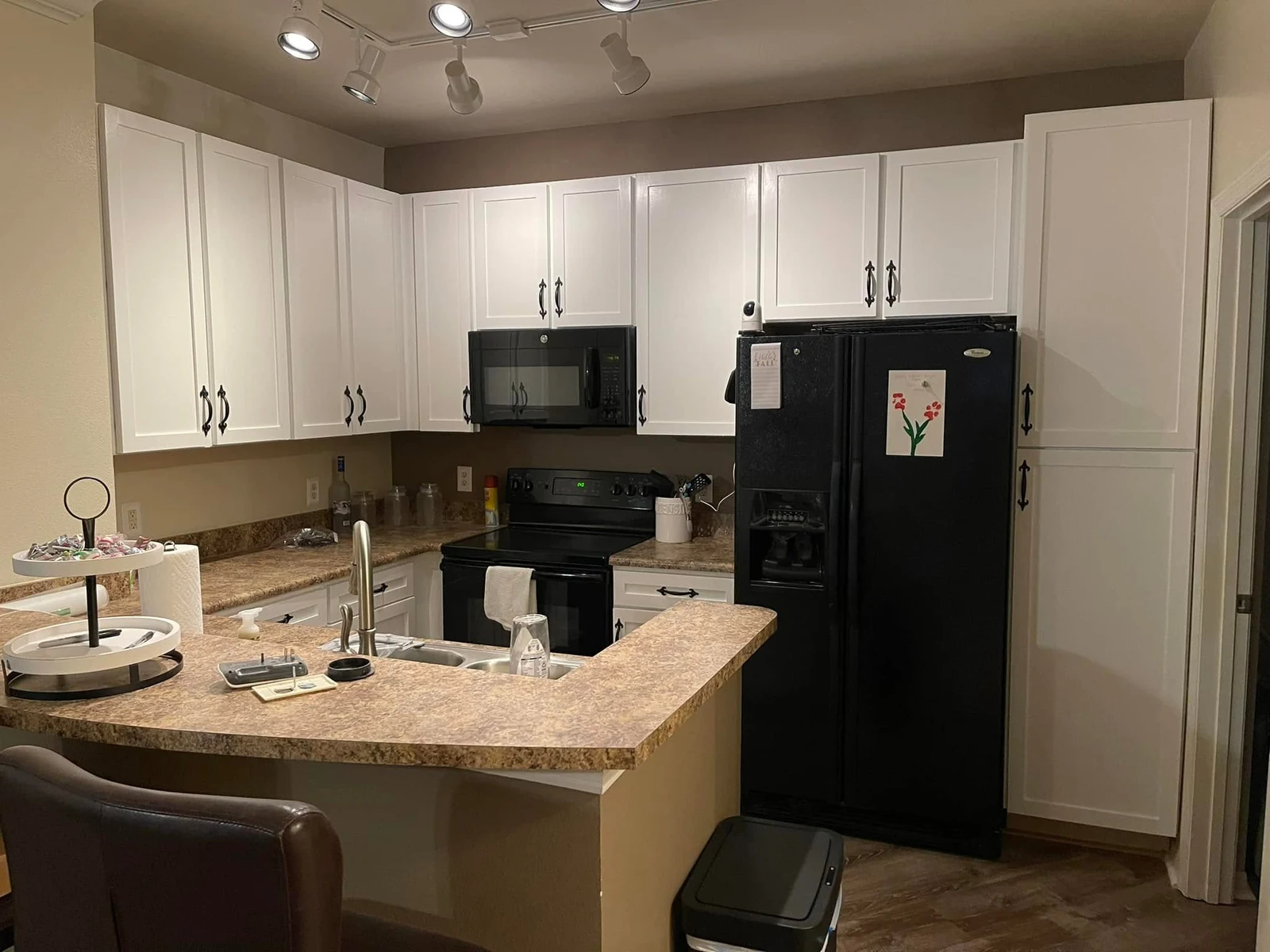 Kitchen after cabinet refinishing, with crisp white doors and dark pulls