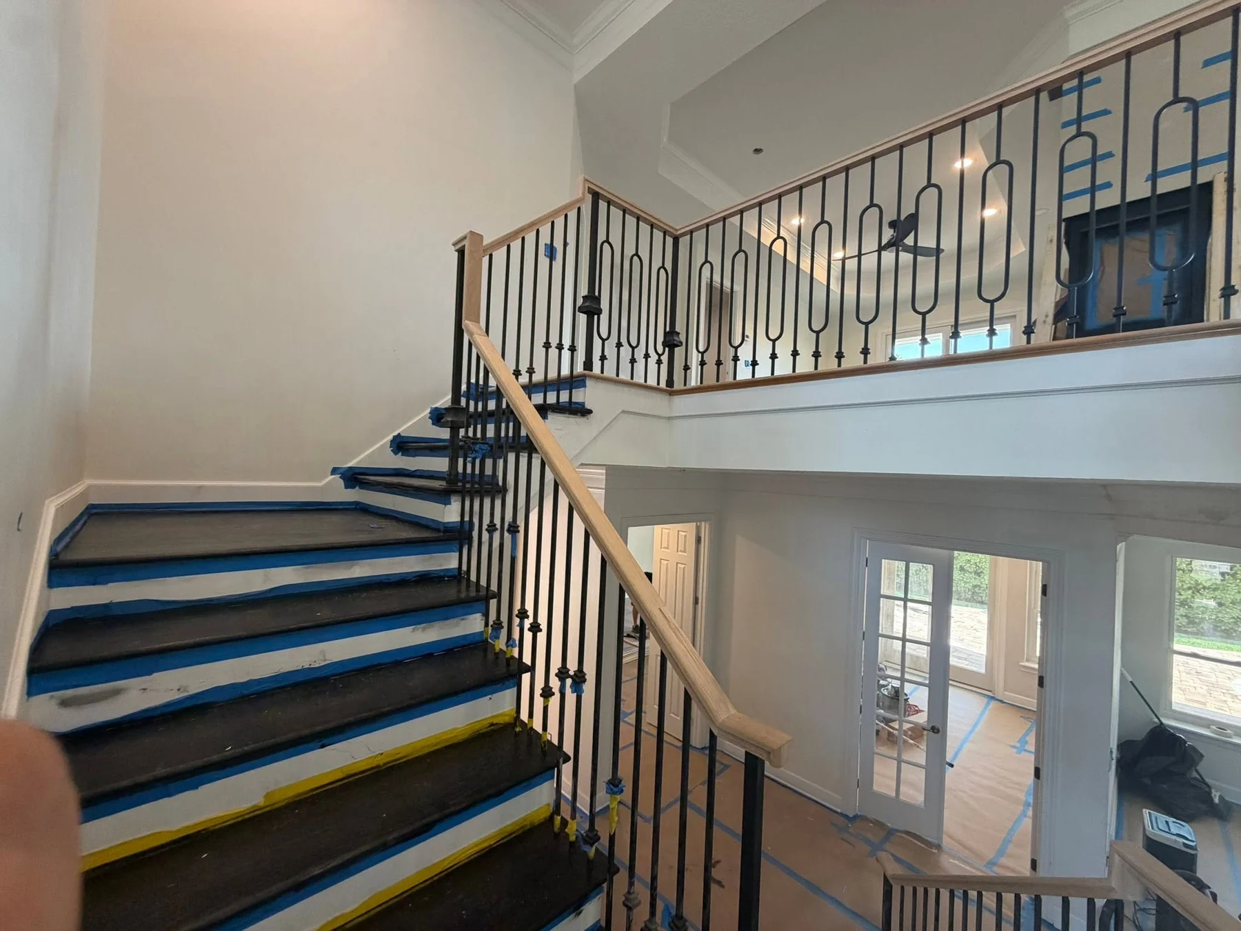 Wood stair rails and black metal balusters during final finishing work